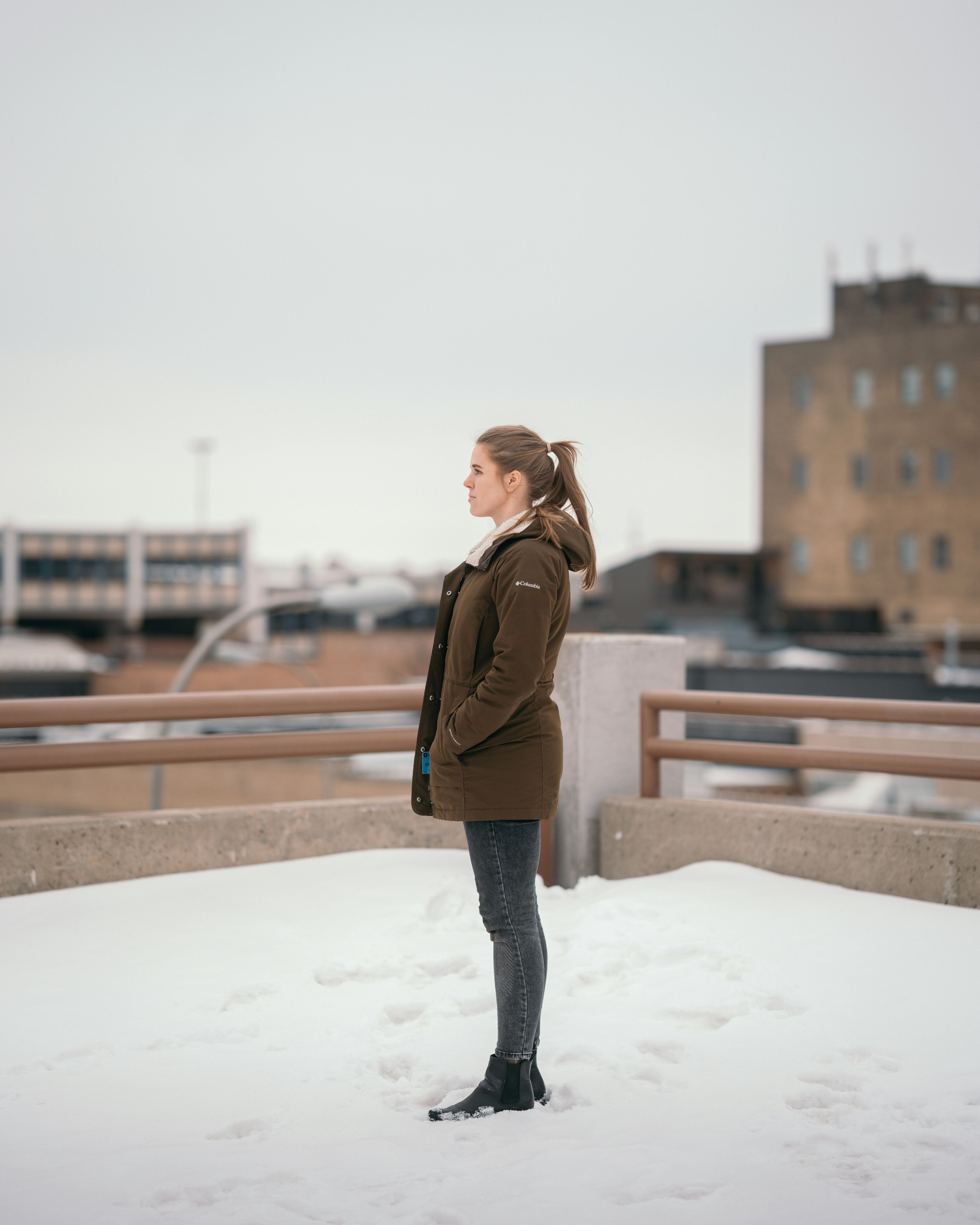 woman in brown leather jacket standing on snow covered ground during daytime